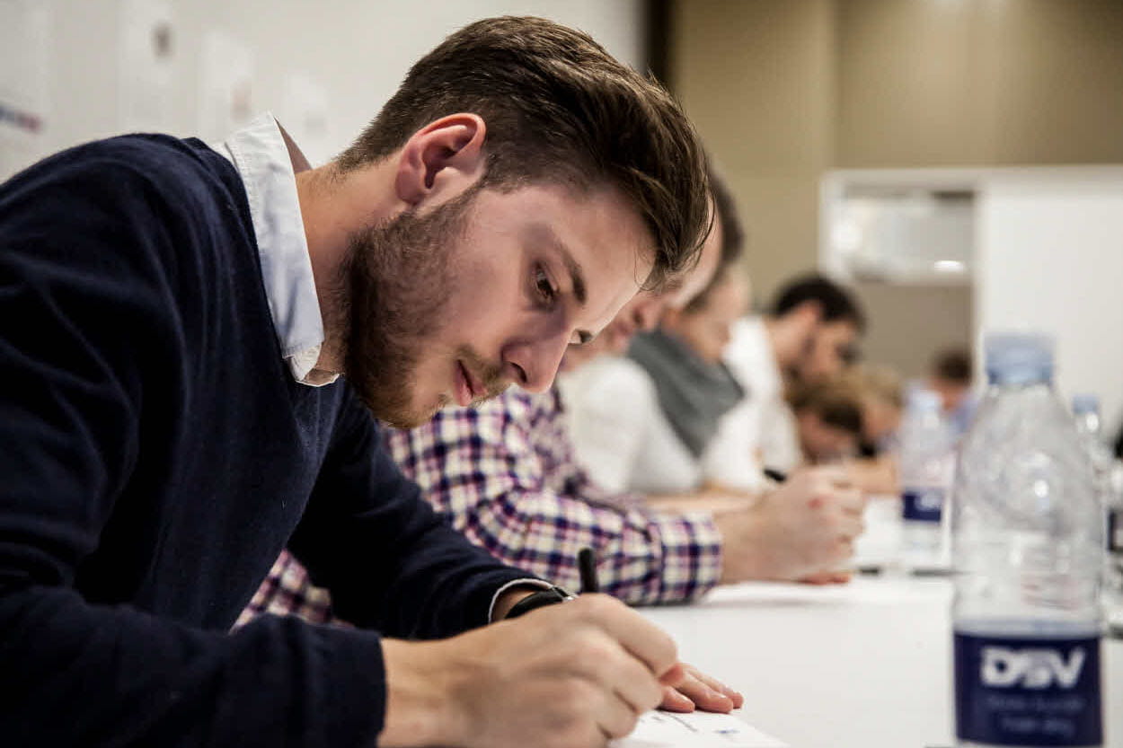 Jovem estagiário masculino escrevendo notas em uma sala de conferências